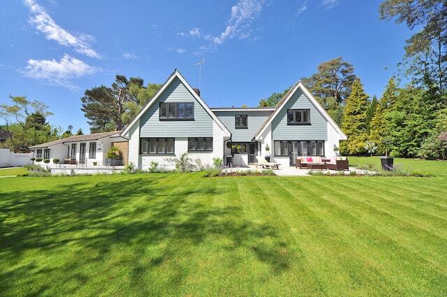 large house with big back yard and dark wicker lawn chairs